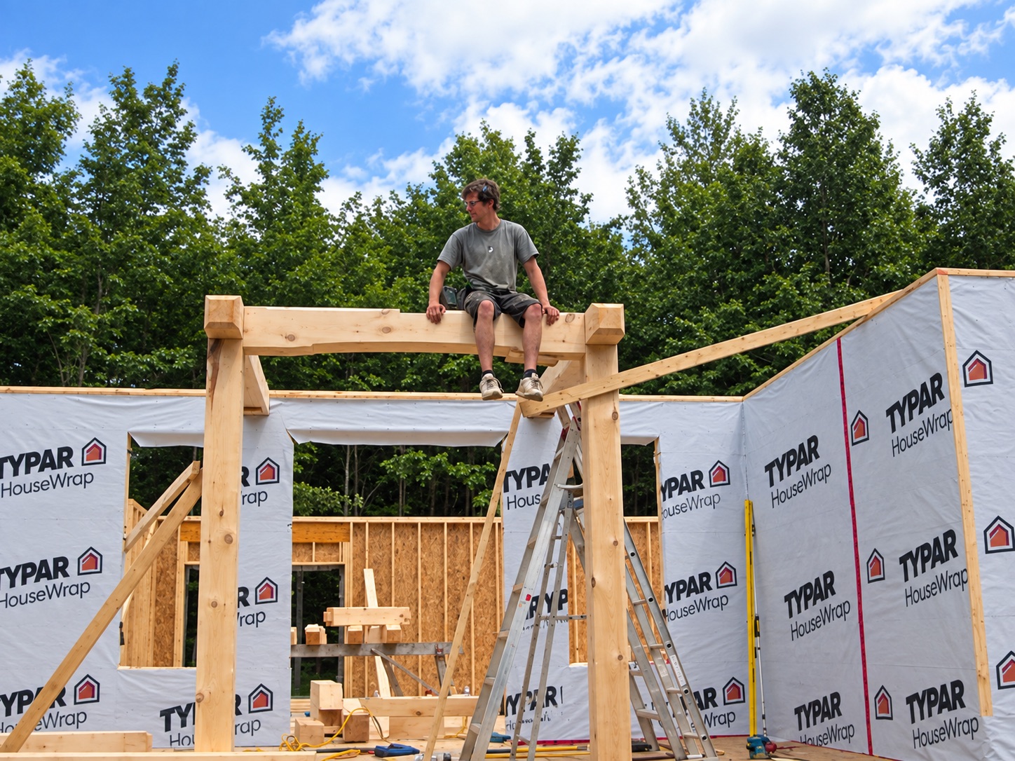 Travis sitting on the frame of a house under construction